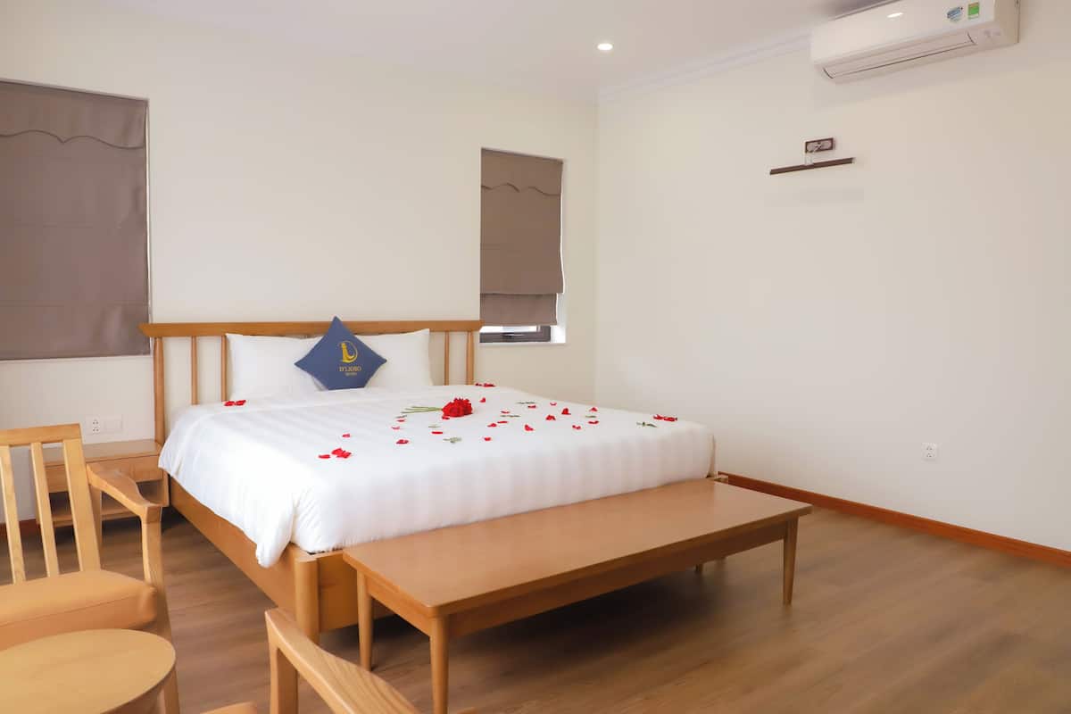 Ein Schlafzimmer mit einem hölzernen Bett, einer Bank, einem Stuhl und einem Nachttisch.