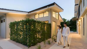 Una casa moderna con un área exterior cubierta, un camino y un seto.