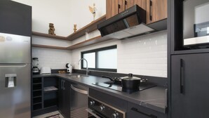 Una cocina moderna con horno empotrado, refrigerador de acero inoxidable y encimera negra.
