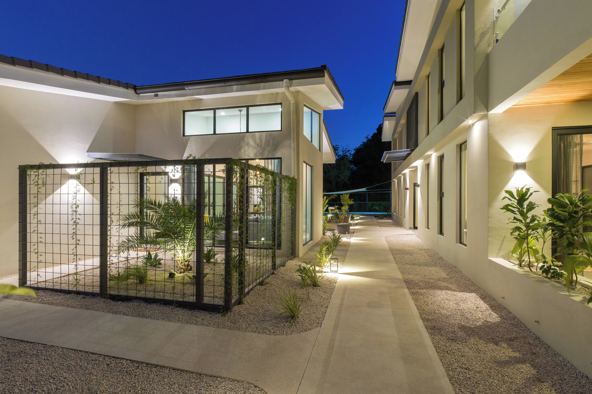 A modern building with a covered outdoor area, a pathway, and potted plants.