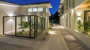 Un edificio moderno con un área exterior cubierta, un sendero y plantas en macetas.