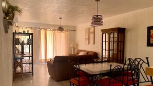 A dining area with a table and chairs, a sofa, and a cabinet.