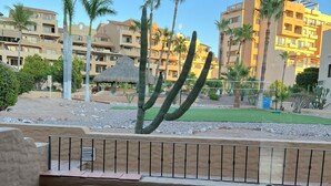 Una terraza con una mesa y una silla, con vista a un patio con palmeras y edificios.