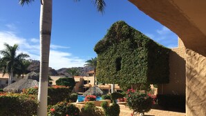 Un resort con piscina, palmeras y un edificio de techo de paja.