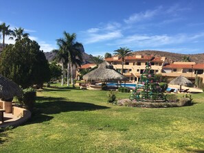 A resort with a swimming pool, thatched-roof structures, and a Christmas tree.