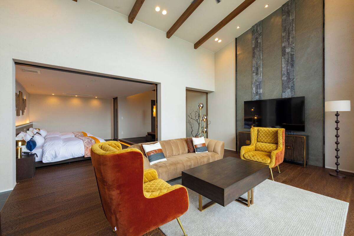 Una sala de estar moderna con un sofá, dos sillones, una mesa de centro y un televisor de pantalla plana.