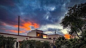 Una casa moderna con techo plano, balcón y entrada pavimentada.