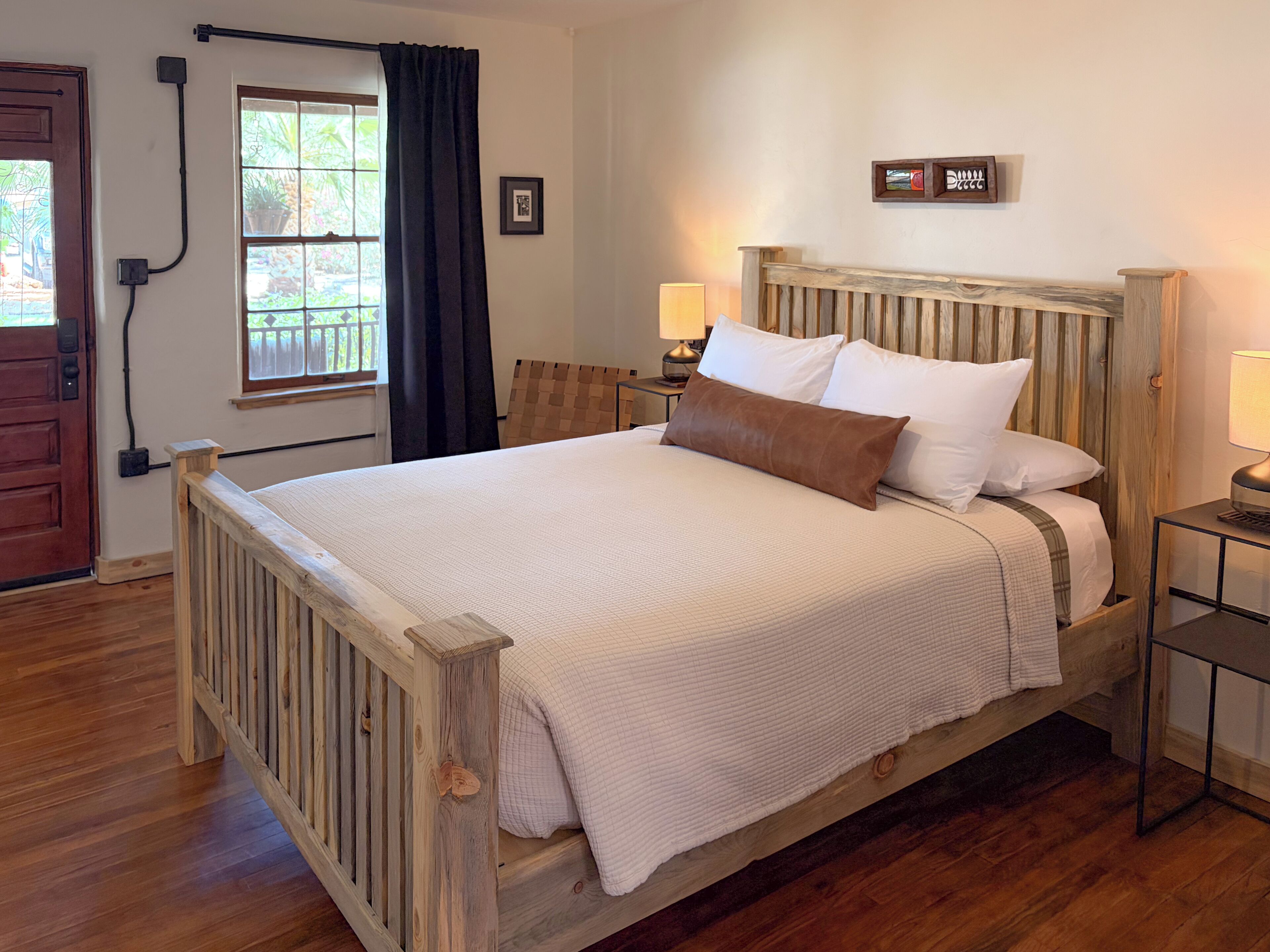 A wooden bed with a headboard, two bedside lamps, and a window with curtains.
