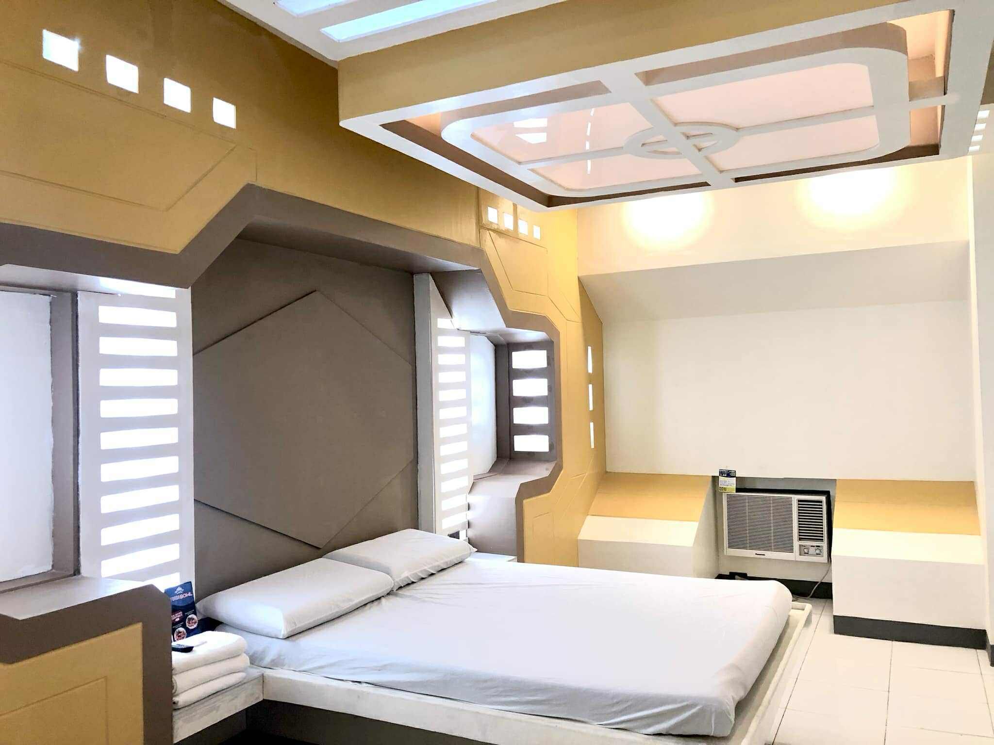Une chambre moderne avec un grand lit, une tête de lit intégrée et une lucarne.