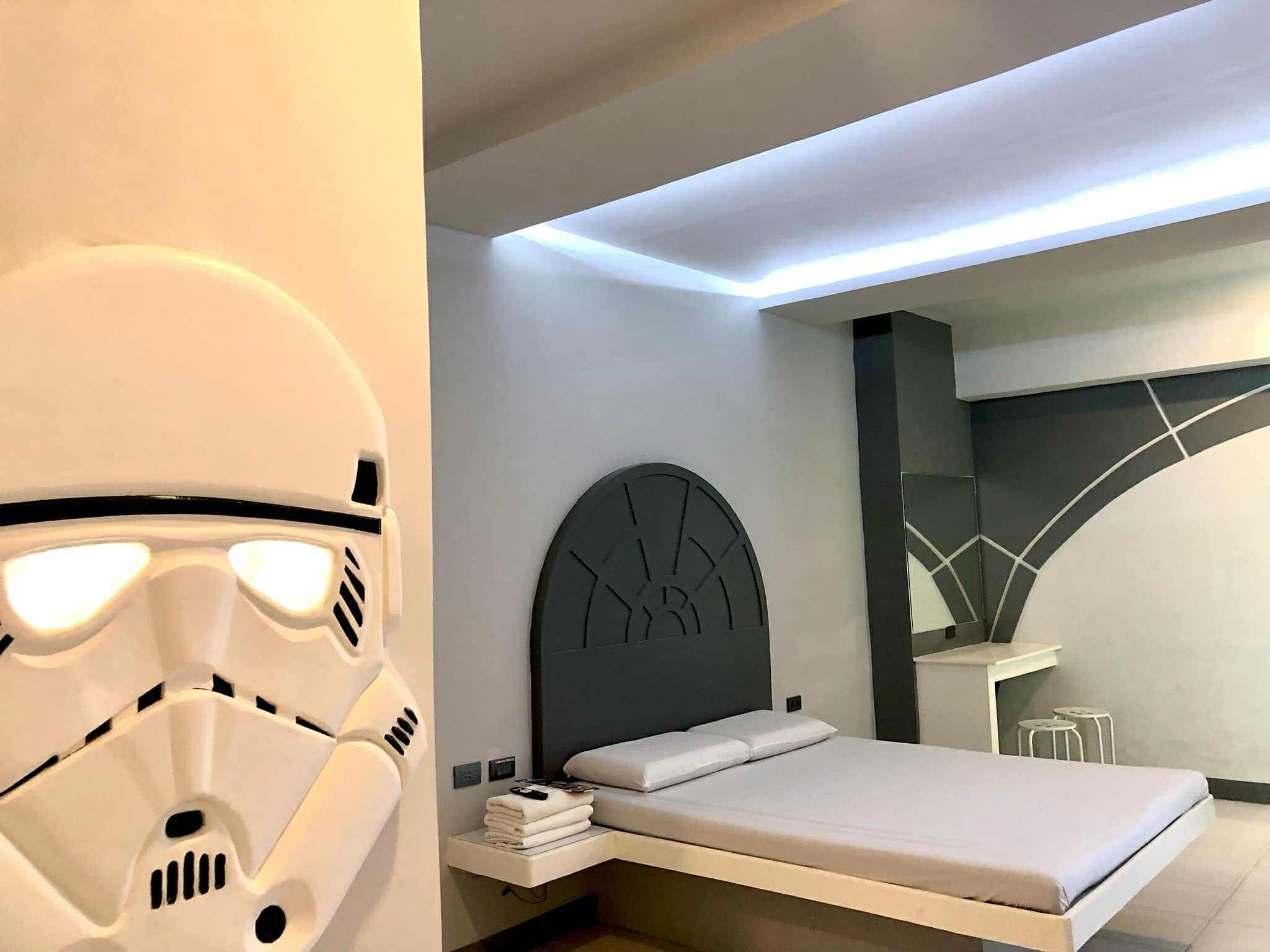 A modern bedroom with a bed, bedside table, and a wall-mounted headboard.