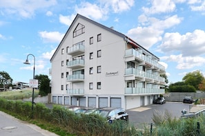 A multi-story building with balconies, a sign reading 'Seetempel,' and several cars parked in front.