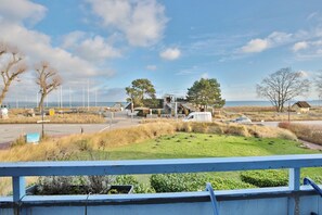 A coastal property with a large house, a white van, and a grassy area with trees. - Seetempel Apartment 26 "Seehase" - Seetempel (Scharbeutz)