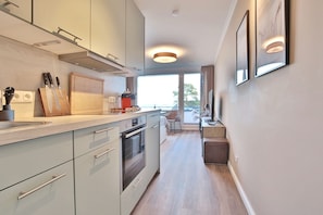 A modern kitchen with a central island, built-in oven, and a dining area with a view.