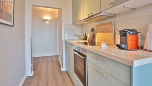 Eine moderne Küche mit hellen Holzschränken, Edelstahlgeräten und einer Arbeitsplatte mit Kaffeemaschine und Messerblock.
