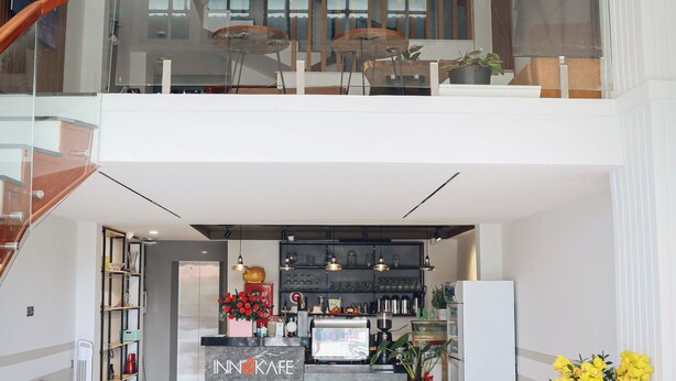 A spacious, modern kitchen with a central island, a dining area with wooden tables, and a staircase leading to an upper level. - Vinh Tuan Hotel (Xuan Huong - Da Lat)