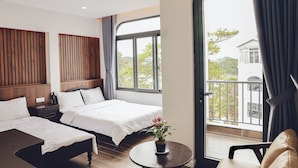 A hotel room with two beds, a small table with a potted plant, and a balcony with a view of the outside. - Vinh Tuan Hotel (Xuan Huong - Da Lat)