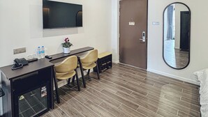 A hotel room with a desk, chairs, a flat-screen TV, a mirror, and a door with a WiFi sign. - Vinh Tuan Hotel (Xuan Huong - Da Lat)