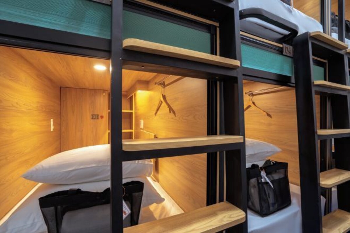 Ein Stockbett mit Holtzrahmen und einem kleinen Regal.