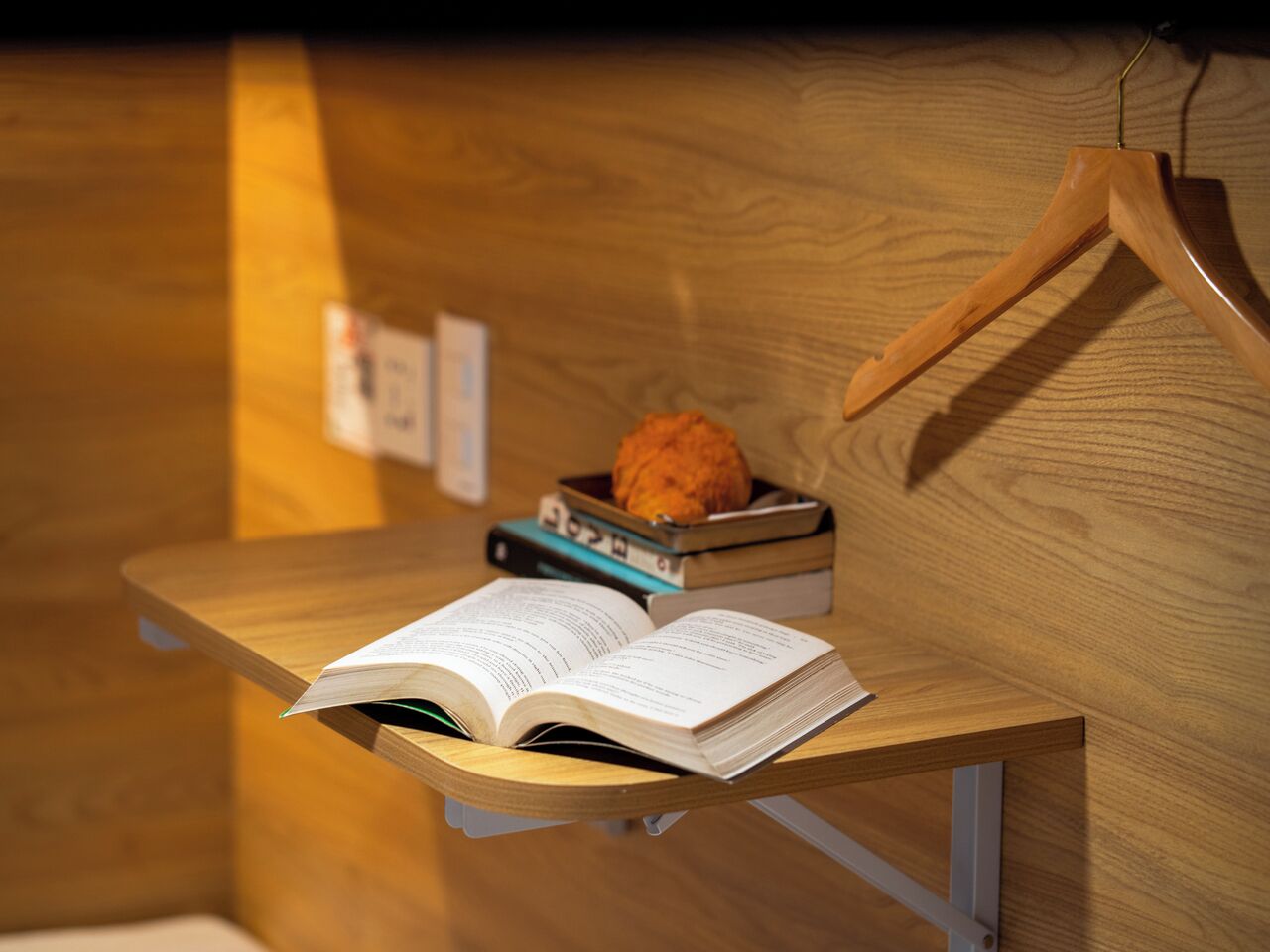 A wooden desk with an open book, a small box, and a cookie.