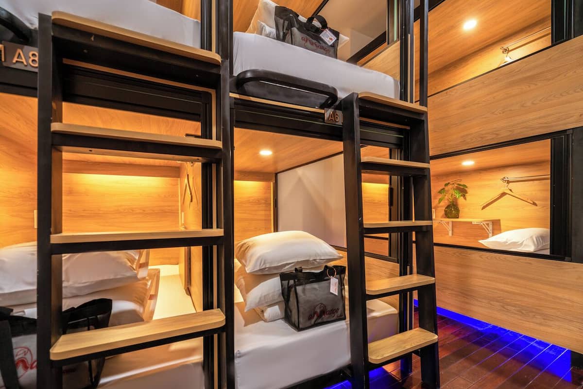 Dormitorio con literas de madera, una mesita de noche pequeña y una planta colgante.
