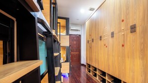 Un vestuario con taquillas de madera, un banco de madera y una puerta que da a otra habitación.
