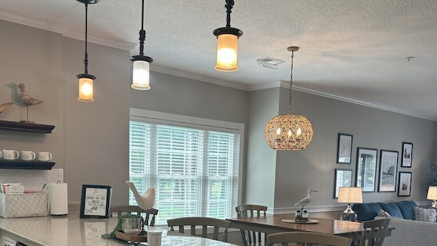 A modern kitchen with a central island, pendant lights, and a dining area with a sofa. - Birdie on the Green in Myrtle wood (Myrtle Beach)