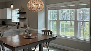 A spacious kitchen with a dining area, large windows, and a hanging light fixture. - Birdie on the Green in Myrtle wood (Myrtle Beach)