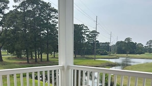 A covered outdoor seating area with wicker furniture and a view of a water body. - Birdie on the Green in Myrtle wood (Myrtle Beach)