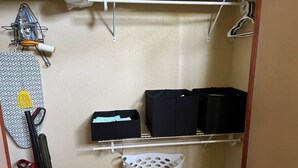 Un espace dédié à la lessive, comprenant un étendoir, un aspirateur, des boîtes de rangement et un panier à linge.