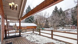 Eine Holzterrasse mit Metallgeländer, einer hölzernen Bank und einem mit Schnee bedeckten Boden.
