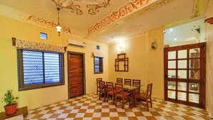 A dining area with a checkered floor, wooden furniture, and decorative ceiling patterns. - Tryambakam Villa (Bhilwara)
