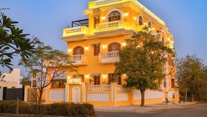 A multi-story building with balconies and a gated entrance. - Tryambakam Villa (Bhilwara)