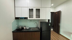 Eine kleine Küche mit weißen Schränken, einem schwarzen Kühlschrank und einem Spülbecken.