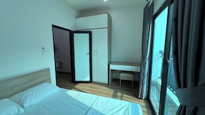 Ein Hotelzimmer mit Bett, Schreibtisch, Kleiderschrank und einem durch eine geöffnete Tür einsehbarer Badezimmer.