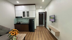 Ein gemütlicher Wohnraum mit einer Küchenzeile, einem Essbereich mit Tisch und Sonnenblumen, einer Couch und einem an der Wand befestigten Fernseher.