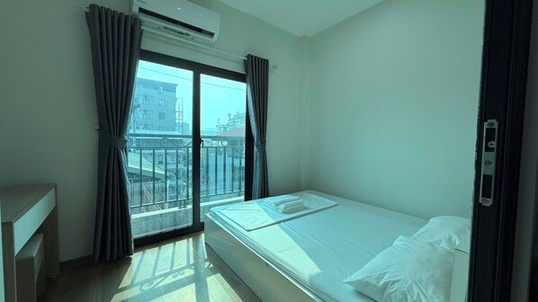A hotel room with a bed, a desk, and a window with curtains. - Era Apartment Doan Ke Thien  (Hanoi)