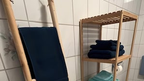 Ein Badezimmer mit einem hölzernen Handtuchhalter, einer Ablage mit gefalteten Handtüchern und einer Toilette.
