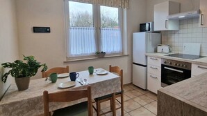 Une cuisine compacte comprenant une table à manger, des chaises, un réfrigérateur, un four à micro-ondes et une cuisinière.