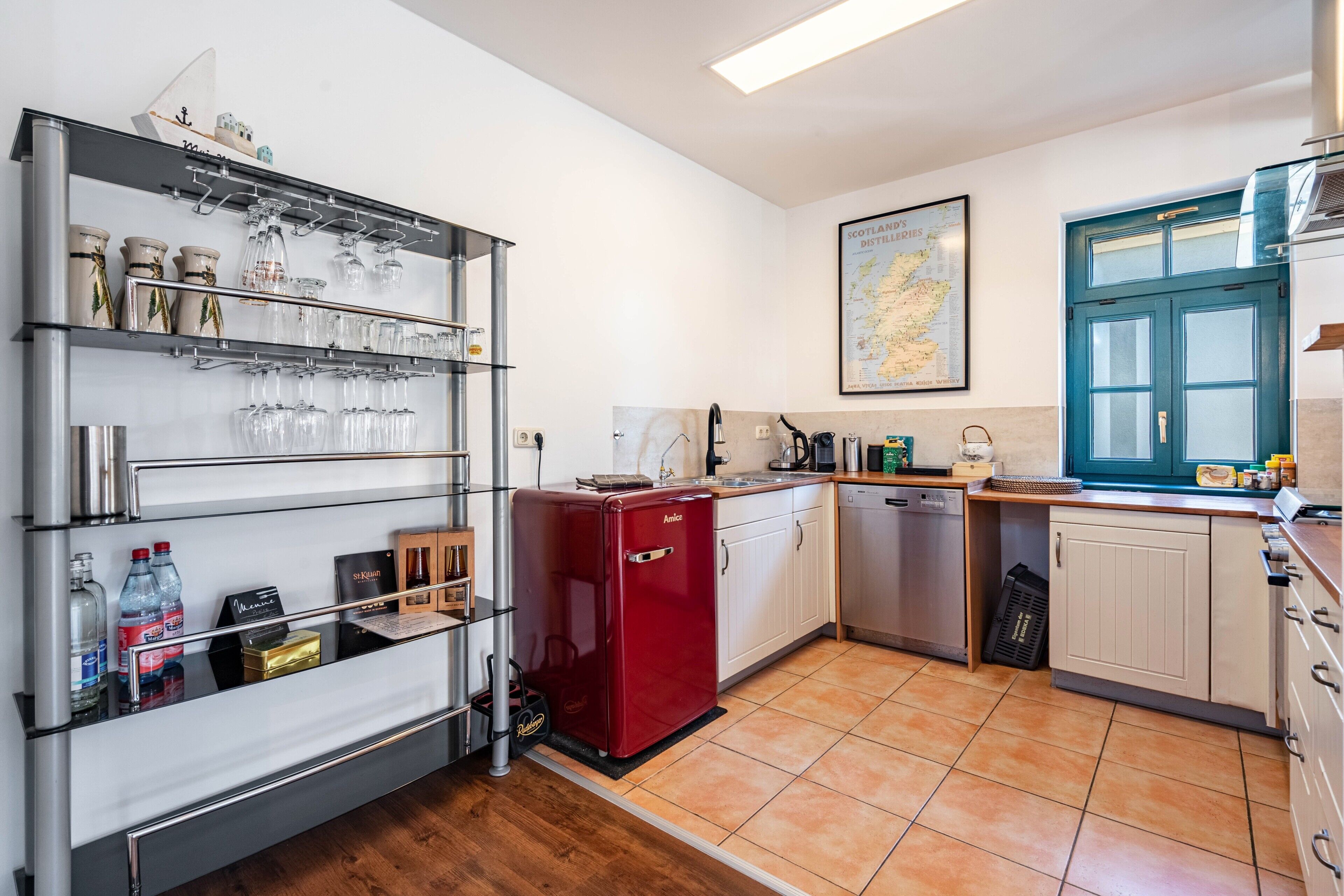 A kitchen with a red refrigerator, a wine rack, and a map on the wall.