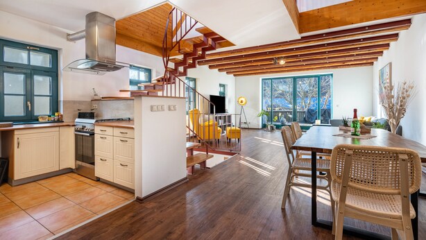 Eine moderne Küche mit Holzbalken, einer Treppe und einem Essbereich mit Stühlen.