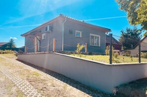 Ein Wohngebäude mit befestigter Auffahrt, umzäunter Garten und blauem Himmel.