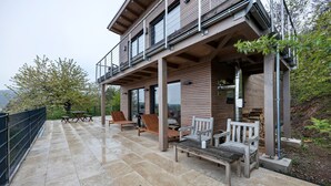 A modern house with a covered patio, outdoor furniture, and a view of the surrounding landscape. - Holiday Home 'Mit Panoramablick' with Mountain View, Shared Terrace and Wi-Fi (Gernrode)