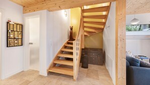 A wooden staircase leading to a second floor, a wall-mounted wine rack, and a sofa in a room with a tiled floor. - Holiday Home 'Mit Panoramablick' with Mountain View, Shared Terrace and Wi-Fi (Gernrode)