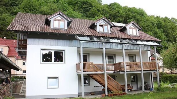 A two-story house with a balcony, a staircase, and a garden.