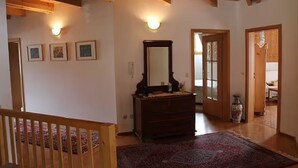 A room with a wooden ceiling, a dresser with a mirror, a rug, and framed pictures on the wall.