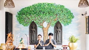 Un mostrador de recepción con un mural de un árbol y dos estatuas, una estatua de Buda y una pequeña estatua de Buda en una cúpula de vidrio.