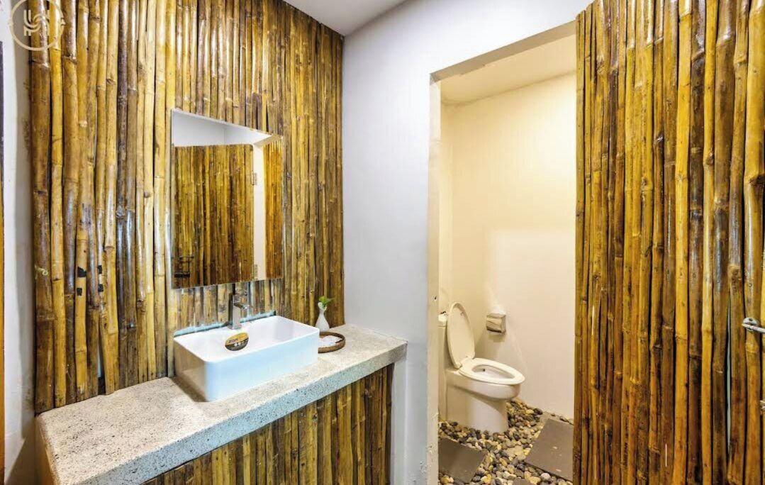 A bathroom with a bamboo wall, a white sink, and a toilet.