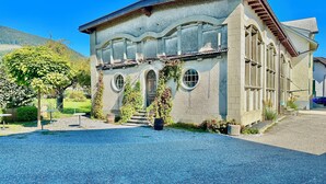 A historic building with a stone facade, arched windows, and a gravel driveway. - Business Apartment Niederbipp (Niederbipp)