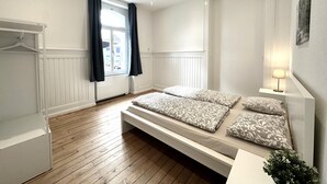 A bedroom with a bed, bedside table, lamp, window with curtains, and a radiator. - Business Apartment Niederbipp (Niederbipp)