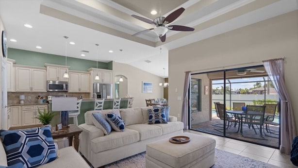 A spacious living room with a sofa, ottoman, and a dining area with a table and chairs.